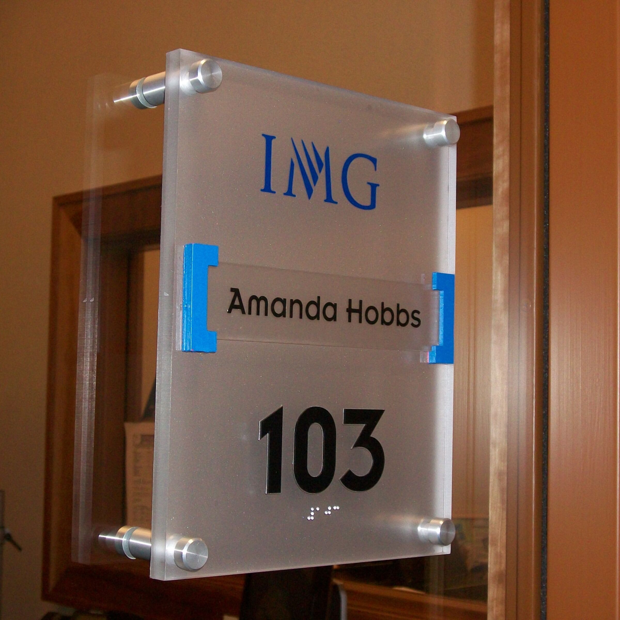 Office sign with room number in tactile characters and Braille.